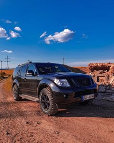 a black truck parked in the middle of a dirt road next to rocks and power lines