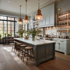 a large kitchen with lots of counter space and lights hanging from the ceiling over the island