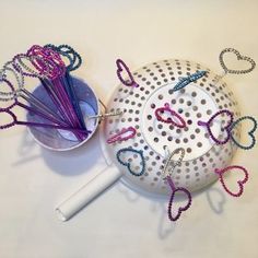 a bowl with scissors and beads on it sitting next to a cup filled with pins