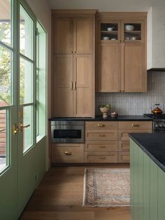 a kitchen with wooden cabinets and black counter tops next to an open door that leads to a deck