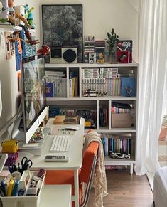 a computer desk sitting in front of a white book shelf filled with lots of books