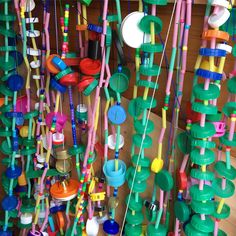 there are many different colored objects hanging from the ceiling in this room, including plastic cups and spoons