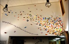 there are many butterflies hanging from the ceiling in this office building that is decorated with words and pictures