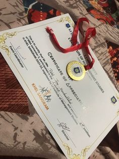 a red ribbon is attached to a white award certificate on top of a patterned table cloth