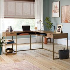 a desk with a laptop on it in front of a window and potted plant