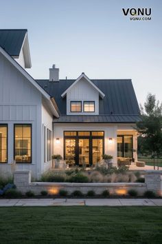 Modern farmhouse with a cozy outdoor space, featuring clean architectural lines and soft exterior lighting. European Modern Farmhouse Exterior, White Modern Cottage Exterior, White House Stained Wood Trim Exterior, Modern Farmhouse Back Porch, Small Modern Farmhouse Exterior, White And Black Farmhouse Exterior, Modern Farmhouse Windows, Black Farmhouse Exterior