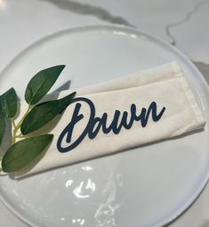 a napkin with the word dawn on it sits on a plate next to a plant