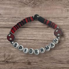 a bracelet with spiderman charms on it sitting on top of a wooden table next to a