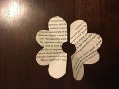 two pieces of paper cut out to look like flowers on a wooden surface with words written in them