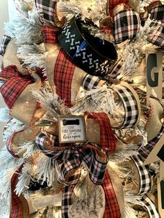 a christmas tree is decorated with plaid ribbon and stockings for the holiday season, as well as an ornament