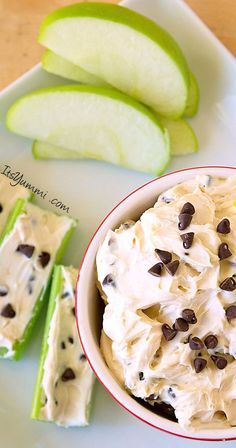 a bowl of ice cream with chocolate chips next to an apple and two pieces of celery