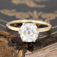 an old - fashioned diamond ring sits on top of a book, next to it's shadow