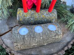 three candles sitting on top of a piece of wood