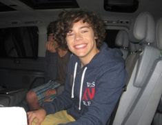 two young men sitting in the back of a van, one is smiling at the camera