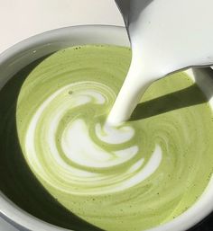 a white spoon pouring green liquid into a bowl