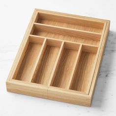 an empty wooden tray on a white marble countertop with the lid open to reveal compartments