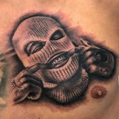 a man's chest with a tattoo on it that has an image of a mask