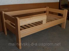 a wooden bed frame sitting on top of a cement floor next to a wood wall