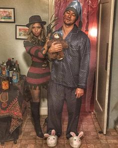 a man and woman dressed in costumes standing next to each other with fake rabbits on their feet