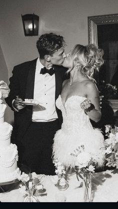 a man and woman kissing in front of a wedding cake