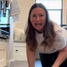 a woman holding a knife in her right hand while standing next to a white counter