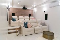 a home theater with white chairs and pillows