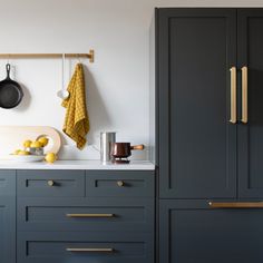 a kitchen with blue cabinets and brass pulls on the handles, hanging pots and pans