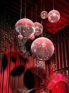 three disco balls hanging from the ceiling in front of a red wall and palm trees