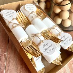 a box filled with lots of gold colored forks and napkins on top of a wooden table