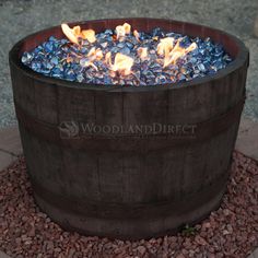 a wooden barrel filled with blue rocks and fire pit sitting on top of a gravel ground