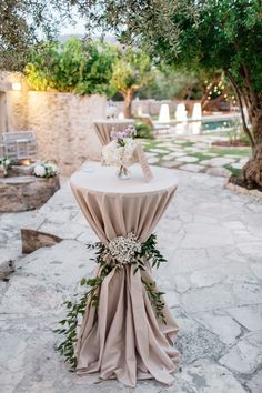 the table is set up with flowers and greenery on it for an outdoor ceremony