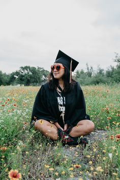 a woman sitting on the ground wearing a graduation cap and sunglasses