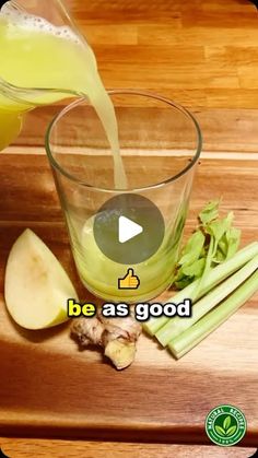 an apple and celery drink being poured into a glass on a cutting board