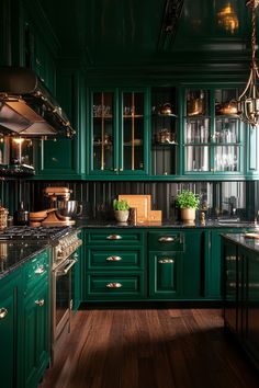 a kitchen with green cabinets and wooden floors is lit by lights from the chandelier