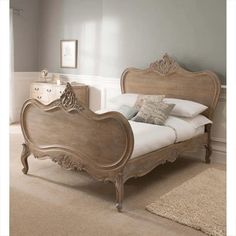 an antique style bed with white linens and wooden headboard, in a bedroom