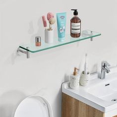 a bathroom with a toilet, sink and shelf above it that has various items on it