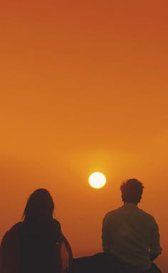 two people watching the sun go down in the sky