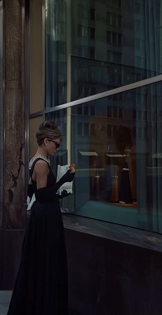 a woman in a black dress is looking at her cell phone