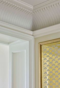 an ornate gold and white painting hangs on the wall next to a framed art piece