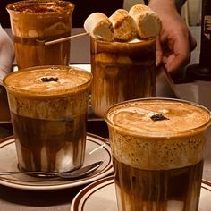 three glasses filled with liquid sitting on top of plates