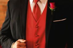 a man in a red tie and black suit with a rose on his lapel