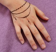 a woman's hand with a beaded bracelet on it and a cross tattoo