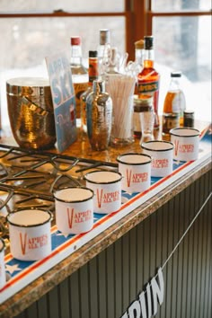 several cups are lined up on a counter with various liquors in front of them