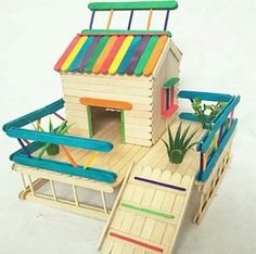 a toy house made out of wood and painted with colorful paint on the roof, sitting in front of a white background