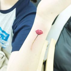 a woman's arm with a small red flower on it