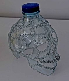 a glass bottle with chains on it sitting on a white counter top next to a blue lid