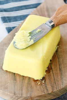 a wooden cutting board topped with a piece of cake and a butter knife on top of it