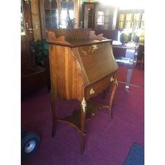 an old wooden desk in the middle of a room with purple carpeted flooring