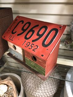 a red birdhouse with numbers on it sitting on top of a shelf in a store