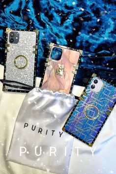 three cell phones sitting next to each other on a white cloth covered surface with the words puritty written below them